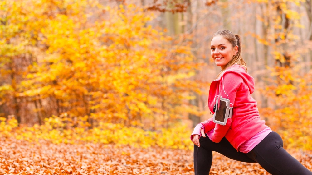 Una ragazza si allena in un bosco durante la stagione autunnale