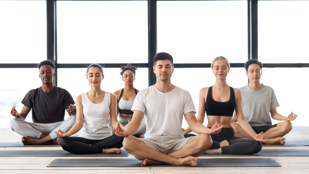 gruppo di persone sedute che meditano - L’importanza della connessione mente-corpo